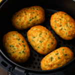 Bolinhos de bacalhau dourados na Air Fryer, servidos com limão em um prato rústico